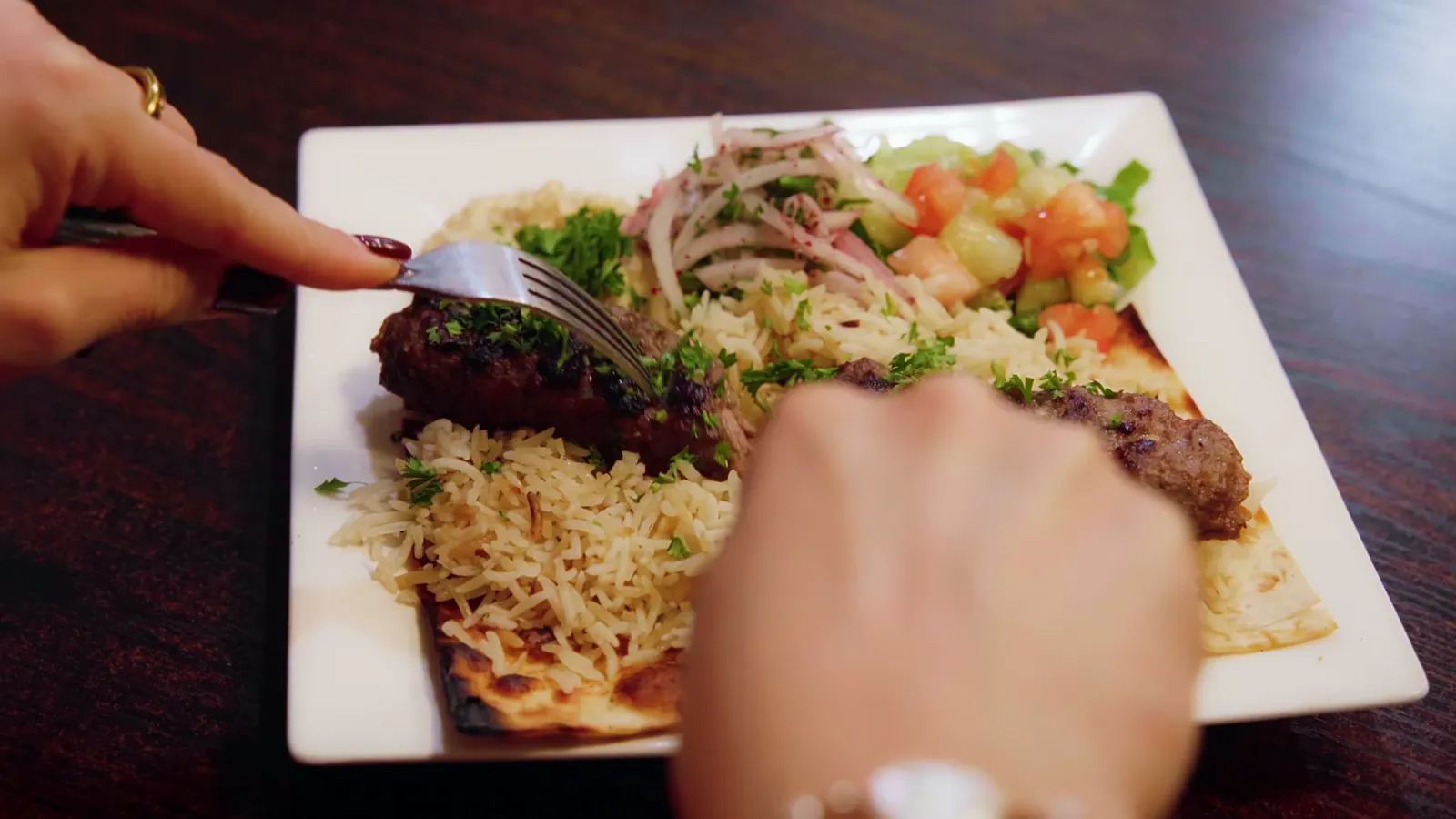 Cutting into an Adana kebab plate