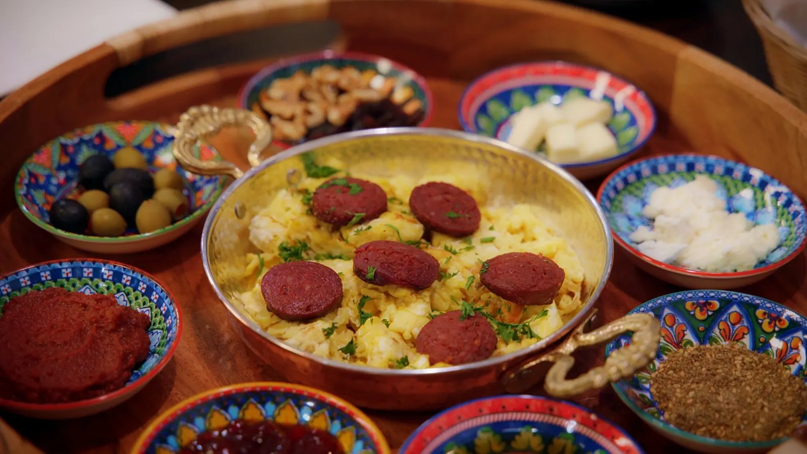 Menemen with sucuk surrounded by small breakfast plates
